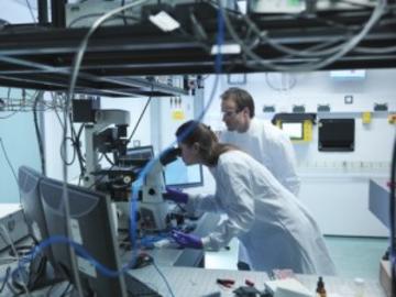 Scientists looking down a microscope at STFC