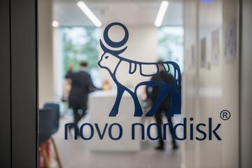 Glass door with Novo Nordisk logo, two people are standing in the background laboratory