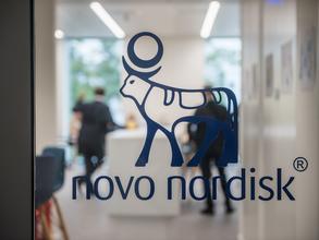 Glass door with Novo Nordisk logo, two people are standing in the background laboratory
